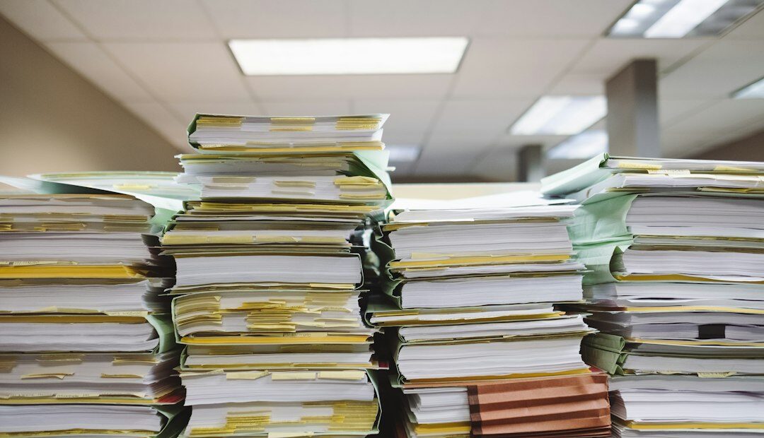 Pilas de documentos y carpetas de archivo sobre un escritorio